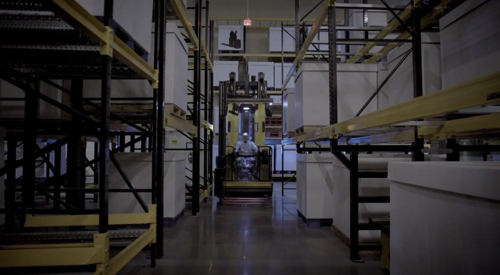 A LiftOne operator driving down a warehouse aisle, from the We Promise film